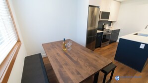 Eine moderne Küche mit Esstisch aus Holz, Edelstahlgeräten und einer blauen Akzentwand.