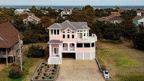 Une grande maison à deux étages, dotée d’un balcon, d’une allée et d’une pelouse.