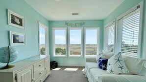 Une chambre avec vue sur la campagne, une commode blanche, un globe terrestre et un lit agrémenté d’oreillers à motifs d’étoiles.