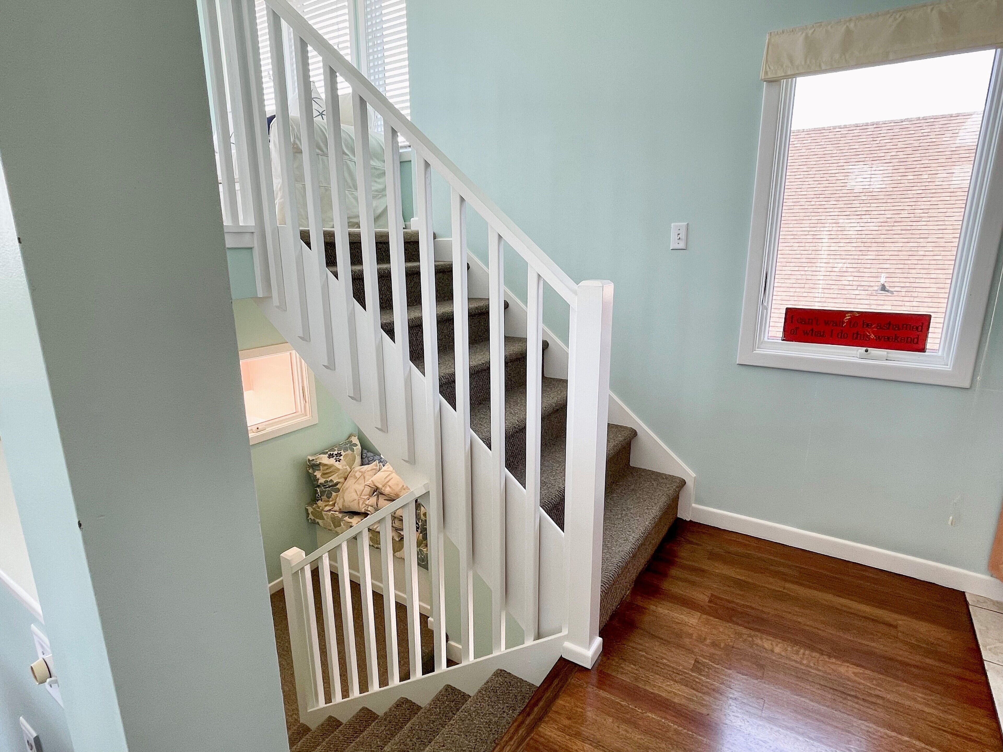 A staircase with white railings and carpeted steps leading to a landing.