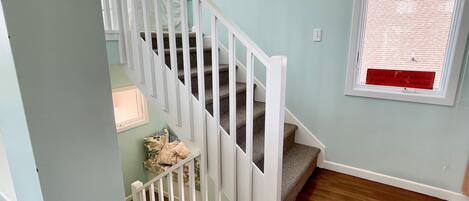 A staircase with white railings and carpeted steps leading to a landing.