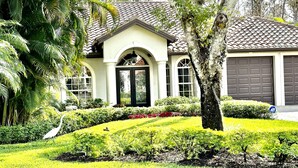 A house with a tiled roof, a black front door, and a garage. - Exquisite Home in Exclusive Community (Naples)