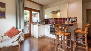 Une cuisine moderne avec des tabourets de bar en bois, une table à manger et une vue sur l’extérieur.