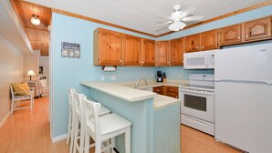 Una cocina con armarios de madera, un refrigerador blanco y una isla integrada con taburetes de bar.