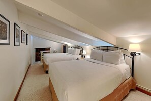 Ein Hotelzimmer mit zwei Betten, einer kleinen Sitzecke und einer Treppe zu einer erhöhten Ebene.