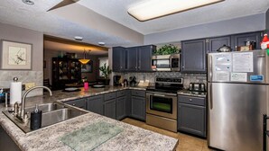 A modern kitchen with granite countertops, stainless steel appliances, and dark cabinetry. - Knolls 1422 - Two Bedroom Apartment, Sleeps 6 (Osage Beach)