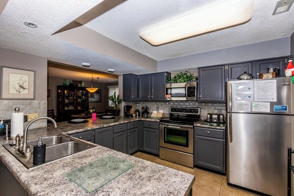 A modern kitchen with granite countertops, stainless steel appliances, and dark cabinetry.
