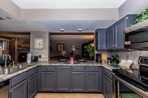 A modern kitchen with dark gray cabinets, stainless steel appliances, and a granite countertop.