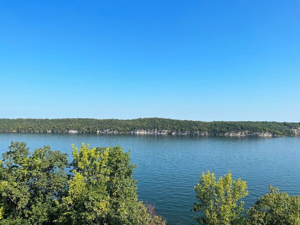 A lake with a forested shoreline and a clear sky.