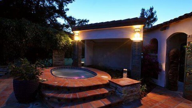 A hot tub with a stone exterior and steps leading up to it, surrounded by a patio area with a pergola overhead. - Three bedroom/three bath resort style home with saltwater pool and spa  (Three Rivers)