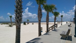 A beach walkway with palm trees, a bench, and a sign indicating 'SISSIPPI 7 COAST'.