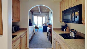 A kitchen with wooden cabinets, a microwave, a kettle, and a stove. - 🌲Timberline 215 Studio Deluxe ~ Hot Tub~Pool~WiFi~Ski-in/out~Local Shuttle🌲 (Snowmass Village)