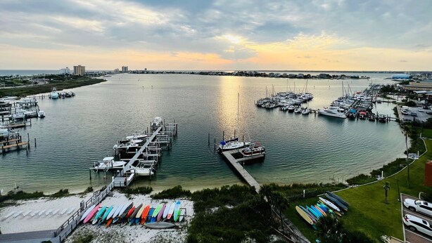 Uma marina com barcos atracados, um cais e uma praia com pranchas de surf.