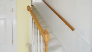 A staircase with wooden balusters and a white handrail.