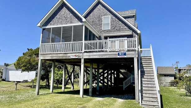 A two-story house with a balcony, a covered porch, and a wooden deck.
