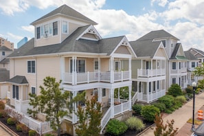 A row of two-story houses with balconies, a front porch, and a small garden area.