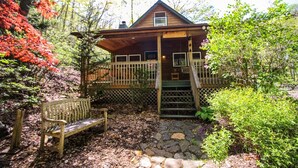 Een chalet met een veranda, een houten bankje en een pad van stenen.