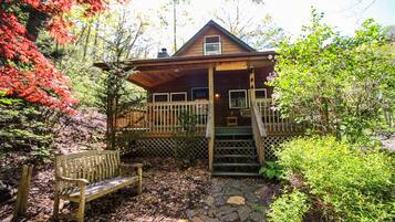 Une cabane dotée d’une véranda, d’un banc en bois et d’un sentier pavé de pierres.