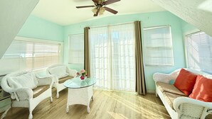 A room with a ceiling fan, two white wicker sofas, a glass coffee table, and a window with blinds. - 2BD Home, 1/2 Block to the Beach, A/C, Pet Friendly, WIFI. - 124 Claressa Ave (Avalon)