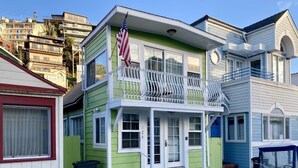 A two-story house with a porch, a flag, and a parked golf cart. - 2BD Home, 1/2 Block to the Beach, A/C, Pet Friendly, WIFI. - 124 Claressa Ave (Avalon)