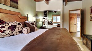 Un dormitorio con una cama grande, techo de madera y una puerta que da a otra habitación.