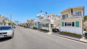 A coastal street with single-story houses, a parked car, and a golf cart. - 324D: Well-appointed Two Story Home + Ample Deck + WIFI + New Carpet - 324 Desca (Avalon)