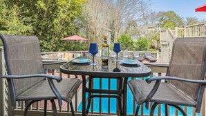 Une terrasse extérieure avec une piscine, entourée de verdure et dotée d’une plateforme en bois.