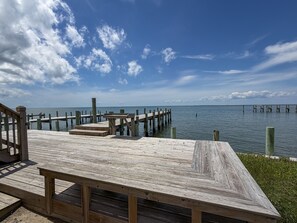 A wooden pier extending into calm waters, with a clear sky above. - Out Of The Blue: Soundfront, spectacular sunsets, private boat dock. (Ocracoke)
