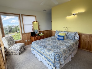 A bedroom with a bed, a chair, a dresser, a mirror, and a window with blinds. - Out Of The Blue: Soundfront, spectacular sunsets, private boat dock. (Ocracoke)