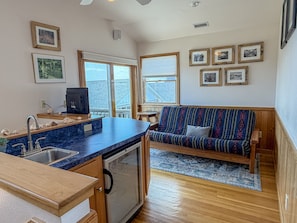 A compact kitchen with a built-in dishwasher, a wooden dining table, and a blue countertop. - Out Of The Blue: Soundfront, spectacular sunsets, private boat dock. (Ocracoke)
