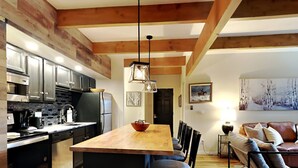 Eine moderne Küche mit Holzbalken, Edelstahlgeräten und einer zentralen Kochinsel mit Barhocker.