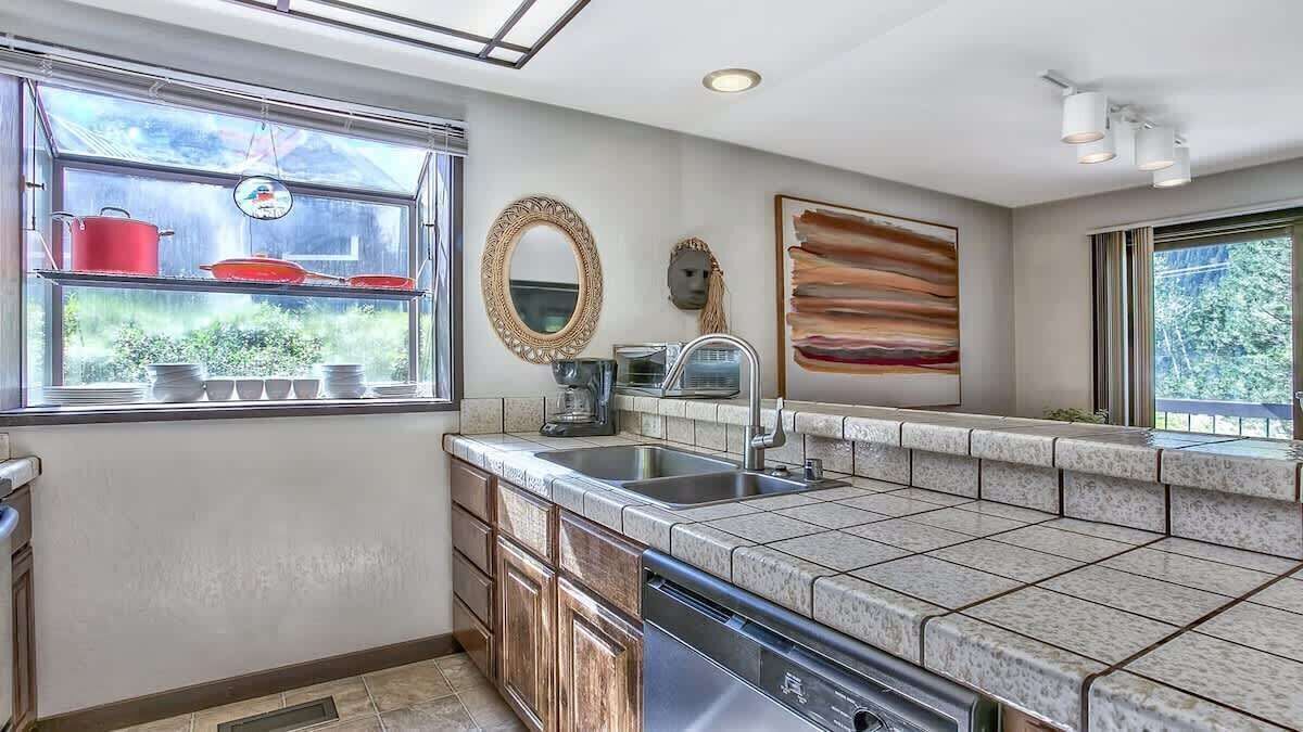 A kitchen with a window, a sink, a dishwasher, and a countertop.