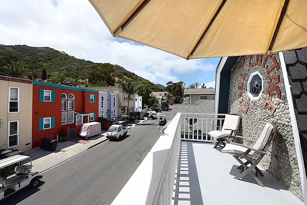 A balcony with a view of a street, a stone wall with a clock, and a parked golf cart.