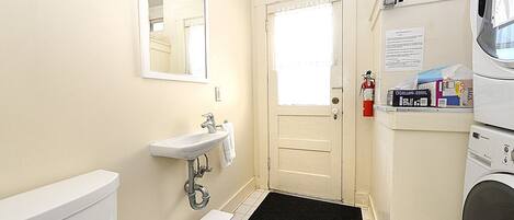 A compact bathroom with a toilet, sink, mirror, and a small step stool.
