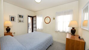 Une chambre à coucher avec un lit, deux tables de chevet avec des lampes, un miroir et des tableaux encadrés accrochés au mur.