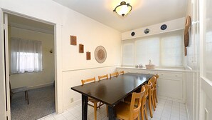Un espace repas comprenant une longue table, des chaises, un luminaire et des éléments décoratifs fixés au mur.