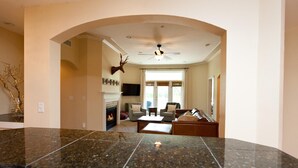 A spacious living room with a fireplace, comfortable seating, and a ceiling fan.