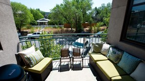 A balcony with wicker furniture, a view of a parking area, and a building in the background.
