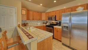 A kitchen with wooden cabinets, a stainless steel refrigerator, a microwave, and a stove.