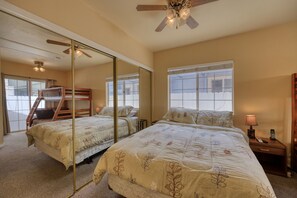 Une chambre avec deux lits, un ventilateur de plafond, un grand miroir et une fenêtre.