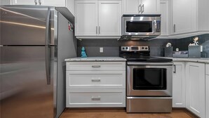 Una cocina moderna con electrodomésticos de acero inoxidable, armarios blancos y un horno empotrado.
