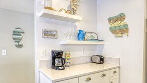 A kitchen with white cabinets, a coffee maker, a toaster, and decorative items on shelves. - 351D: Beautiful Restored Home, 2.5 Blocks from Downtown (Avalon)