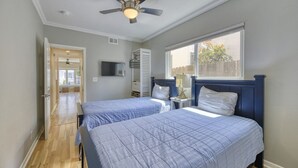 A bedroom with two beds, a ceiling fan, a TV, and a window with a view of the outside. - 351D: Beautiful Restored Home, 2.5 Blocks from Downtown (Avalon)