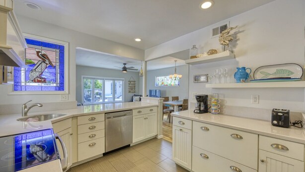 A modern kitchen with white cabinetry, a dishwasher, a coffee maker, and decorative items on shelves. - 351D: Beautiful Restored Home, 2.5 Blocks from Downtown (Avalon)