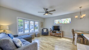 A living room with a sofa, TV, wooden dining table, and a ceiling fan. - 351D: Beautiful Restored Home, 2.5 Blocks from Downtown (Avalon)