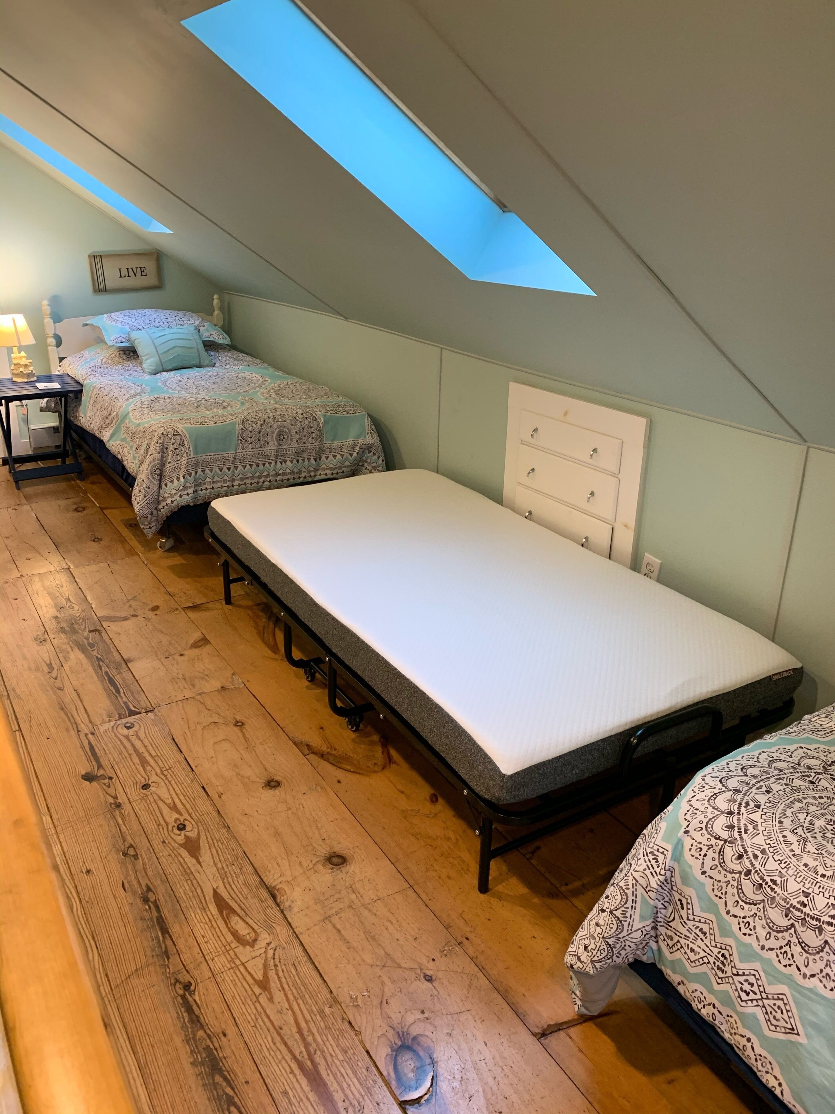 A dorm-style room with two beds, a desk, and a dresser.