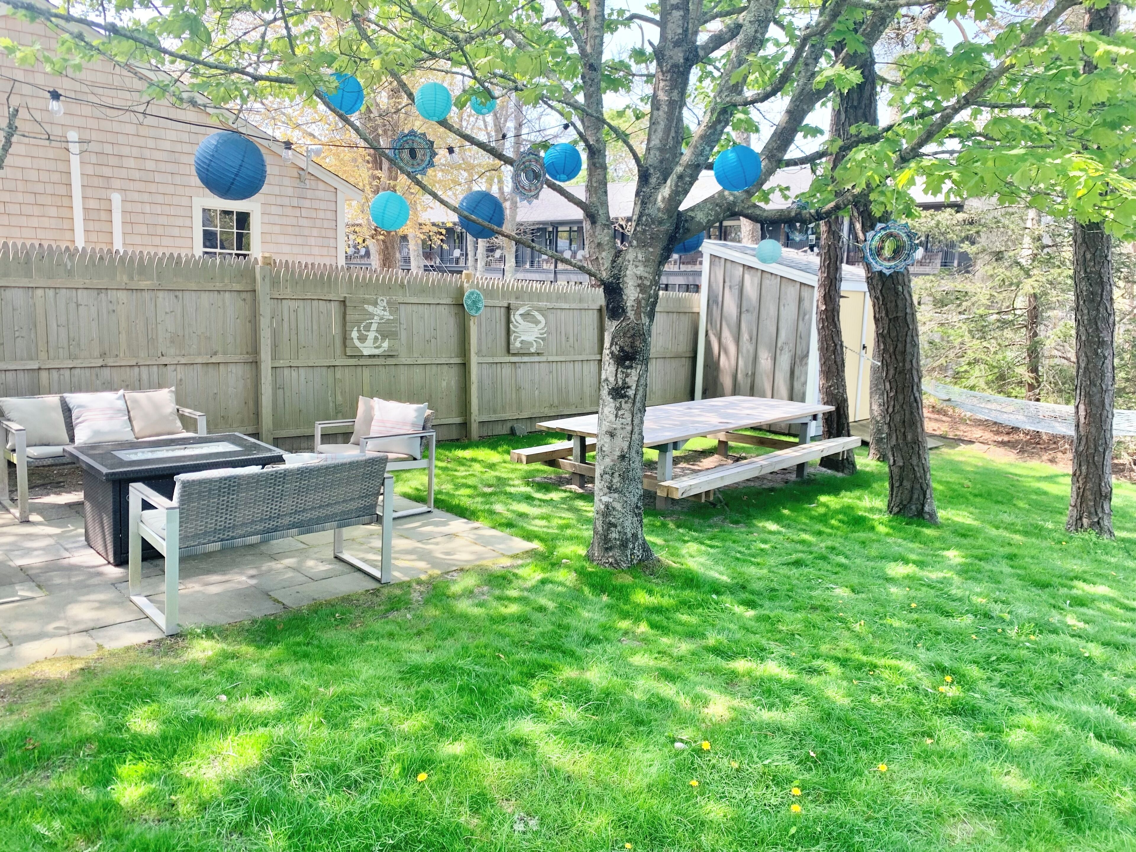 A backyard with a patio area, a wooden fence, and a tree.