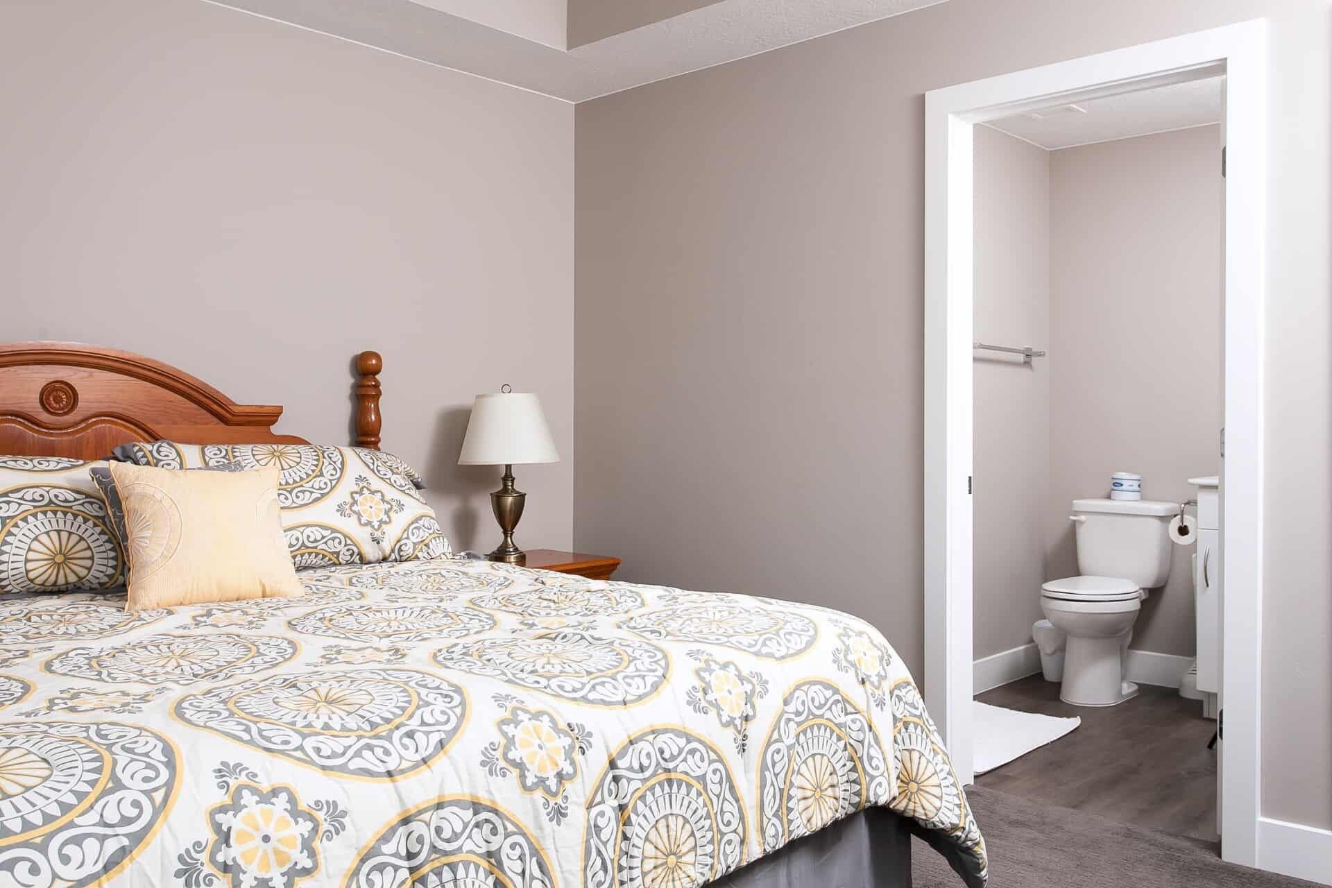 Une chambre avec un grand lit, une table de chevet avec une lampe et une vue sur la salle de bain.