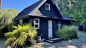 A small, dark blue house with a sloped roof, a front door, and a small porch.