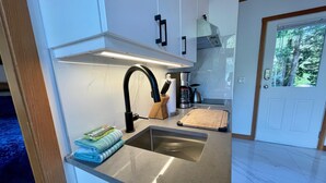 A modern kitchen with a stainless steel sink, a coffee maker, and a cutting board.